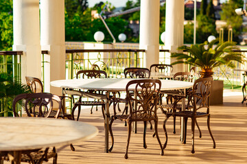 outdoor summer terrace, with cast iron.stylish furniture, in a cafe at sunset