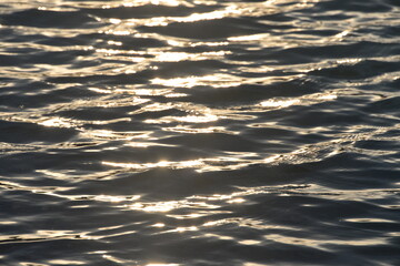 beautiful lake at sunset, the rays of the sun paint the water and small waves in gold, red, orange