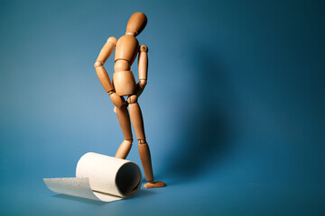Wooden figure sit on a roll of toilet paper. Concept of the problem with digestion.