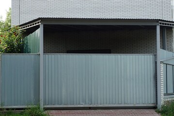 one large gray closed metal gate and part of the fence on the street