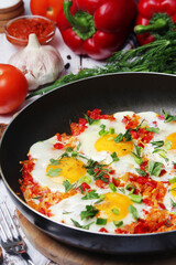Shakshouka with five cooked eggs on top of tomato sauce in cast iron skillet	