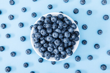 Fresh berries blueberry on blue background. Colorful fruit pattern of blueberries as background. Creative berries concept. Flat lay, top view, copy space