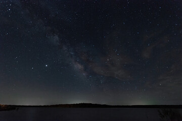 Milky Way galaxy and light wispy clouds over lake at night