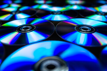 CDs / DVDs lying on a black background with colorful reflections of light.