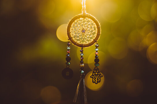 Close up of spiritual dreamcatcher necklace with sacred geometry circle with bokeh background backlit by sunset golden light