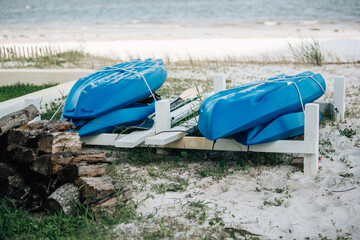 Beach storage of several blue kayaks and recreational small personal water boats paddleboards for summer recreational water sports activities
