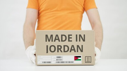 Worker wearing orange uniform puts box with MADE IN JORDAN print on the table - Powered by Adobe