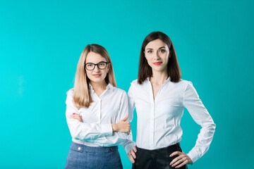 The theme is a female team. Portrait of two young caucasian business women posing in studio on a...