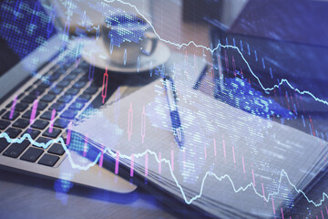Double exposure of forex chart drawing and desktop with coffee and items on table background. Concept of financial market trading