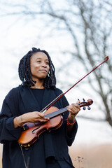 Portrait of black woman musician with violin in nature