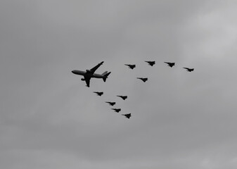Military airplanes flying in V formation with grey and cloudy day at background. Black and white photograhpy Military and aircraft concept