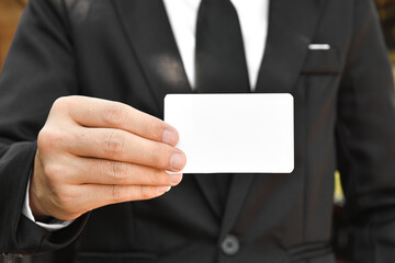 Close-up of businessman holding white piece of paper. Selective focus hand.