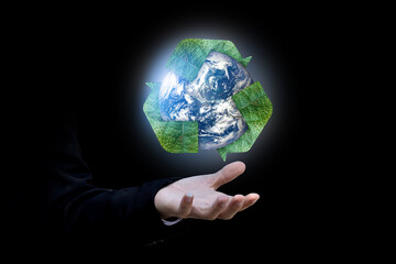 Businessman hand holding Earth and recycle logo over black background. Elements of this image furnished by NASA