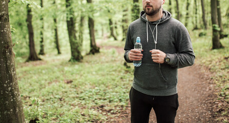 Adult sporty man in forest, park running in the morning