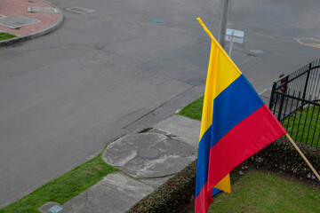 Colombian flag in wooden flagstick  waving with the wind at residential  neighborhood in colombia's independence day celebrations