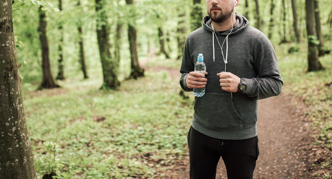 Adult sporty man in forest, park running in the morning