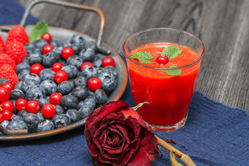 raspberry and blackberry smoothie.
Berry juice with fresh berries and dry rose on a black wooden table, close-up side view.
