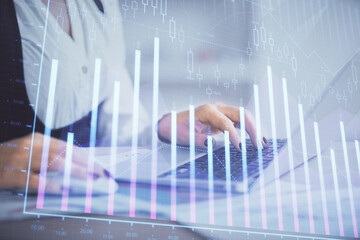 Double exposure of businesswoman hands typing on computer and forex graph hologram drawing. Financial analysis concept.