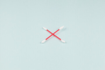 Two crossed ear sticks on a light background. Concept - rejection of cotton swabs based on plastic