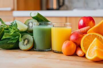 Orange juice and green juice with fresh and raw fruit in the background