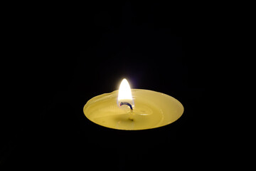 Burning festive tea candle on a black background