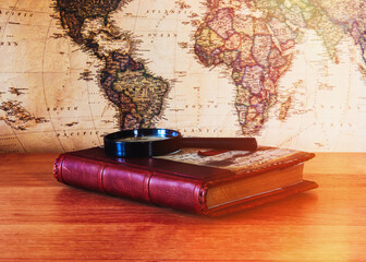 Vintage notebook with a magnifying glass on the background of a vintage card. Travel, tourism concept.