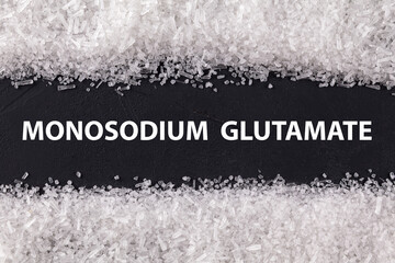 Closeup texture umami on dark background with text Monosodium glutamate . Sodium salt (MSG, E621) used as flavor enhancer. Food ingredient