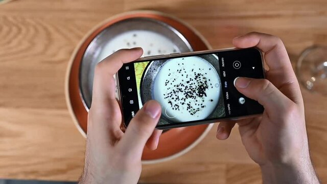 Man hand with smartphone photographing food at restaurant or cafe. High quality footage