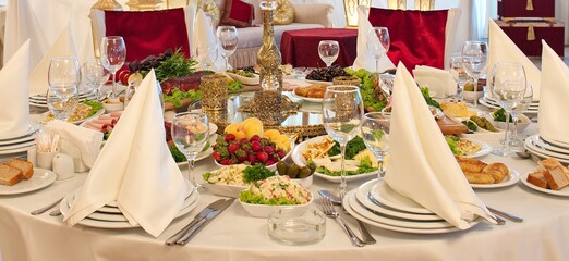 Festive table setting, serving. Table setting. Plates, glasses, food, salads, fruits on the table.
