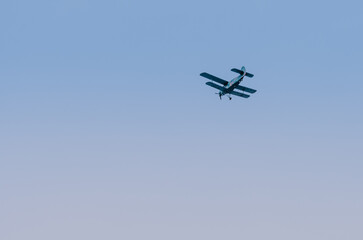 Military biplane flying in clear blue sky