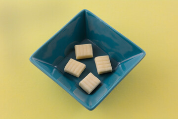 Corn flavored hard candy chews in blue candy dish on yellow background
