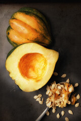 Flat lay image of an Acorn Squash cut in half on a metal baking sheet with a spoon and seeds scooped out with warm side light.