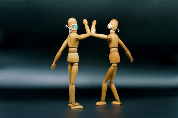 Wooden mannequins with "elbow bumping" greeting