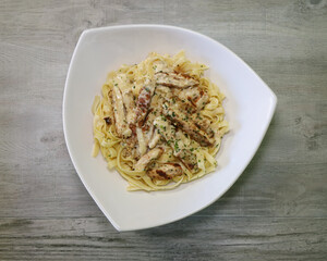 Chicken fettuccine alfredo served on a white plate.
