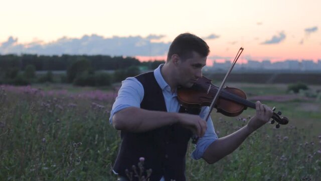 young man violinist smile in the field at sunset playing the violin inspiration 
