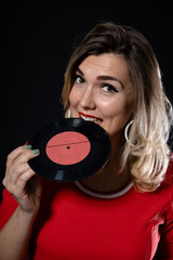 Fototapeta premium happy blonde girl with vinyl records in hand on a black background