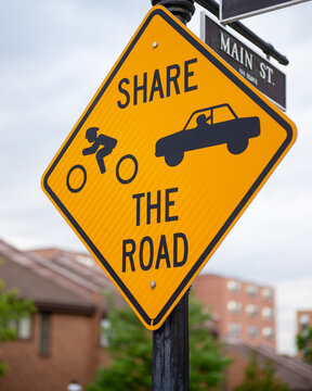 Bright yellow Share the Road sign with bike and car pictures