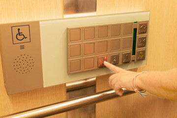 finger pressing on floor number on elevator panel