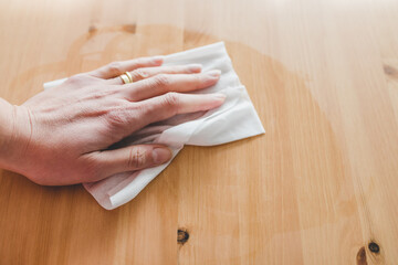 hand cleaning woooden coffee table with disinfectant wet wipe concept of the new normal after...