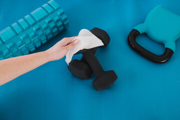 the new normal after covid-19, hand cleaning gym equipment with disinfectant wipe against virus and...