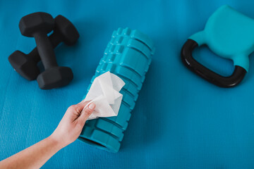 the new normal after covid-19, hand cleaning gym equipment with disinfectant wipe against virus and...