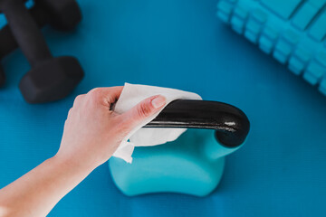 the new normal after covid-19, hand cleaning gym equipment with disinfectant wipe against virus and...