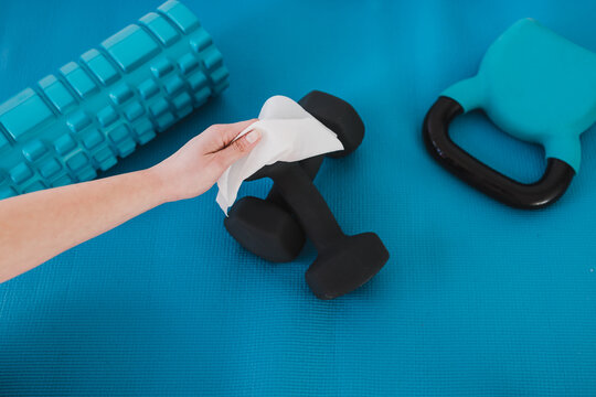 the new normal after covid-19, hand cleaning gym equipment with disinfectant wipe against virus and bacteria