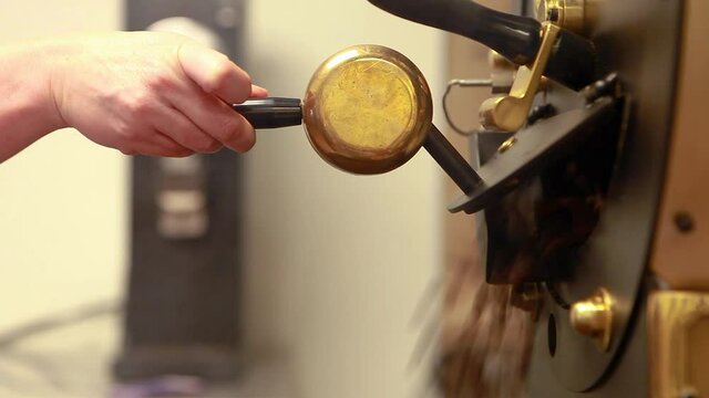 Woman's hands open coffee roasting machine to release freshly roasted coffee beans