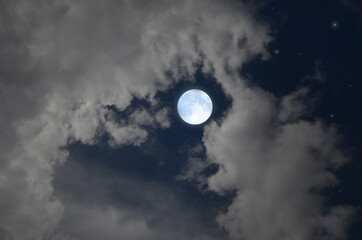 Fototapeta na wymiar Bright full moon and white clouds in blue sky