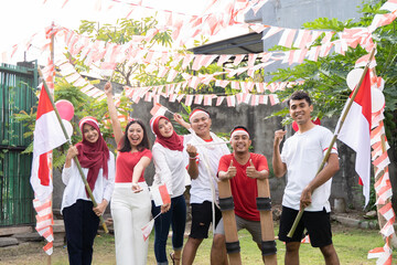 Asian boys and girls smile while carrying and flying the Indonesian flag each wearing the red and...