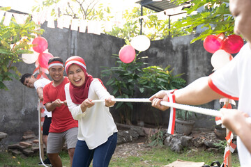 three people in one team tried to pull the rope hard during the tug-of-war competition at Indonesia's Independence Day celebrations