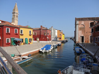 Fototapeta na wymiar colorful houses and boats with reflections in the canal on the island of Burano in Venice