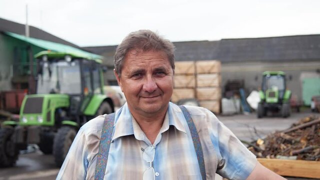 Happy caucasian experienced farmer at organic farmhouse. Cultivating machinery on background. Portraits. Agriculture concept.