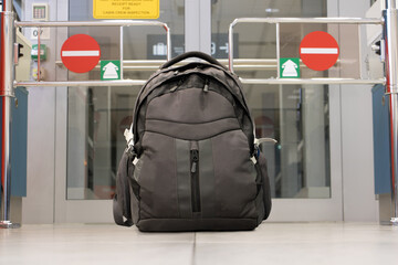 Backpack standing in front of closed door of departure gate at airport terminal. A lonely baggage at the airport.